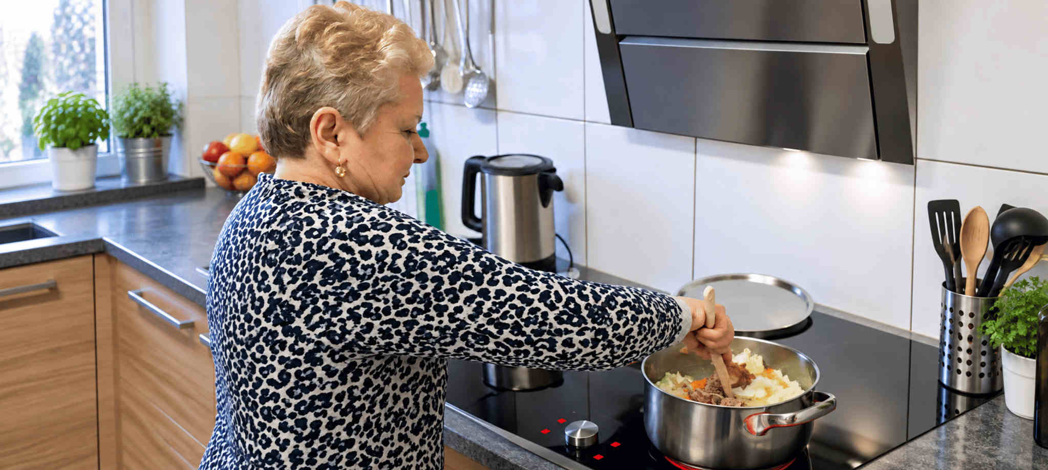 Betreuungsperson und ältere Frau beim gemeinsamen Kochen zu Hause